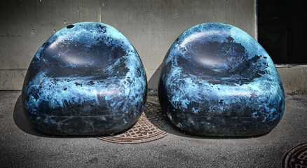 Two old, worn blue plastic chairs on a sidewalk near Slussen in Stockholm, Sweden