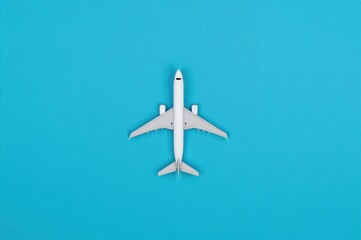Small model aircraft against a blue backdrop with empty space for text. Travel, holiday, tourism, budget airlines theme. Overhead perspective, flat lay.