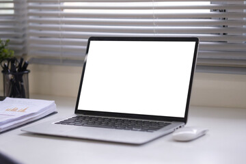 Fototapeta premium Laptop with blank white screen on office desk, ready for design mockup or presentation.