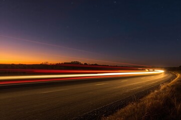 Fototapeta premium Long exposure shot of a vehicle speeding past at dusk, leaving a colorful light trail