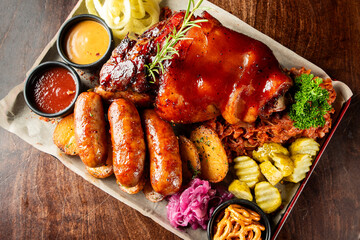 Rustic meat platter with glazed pork knuckle, grilled sausages, roasted potatoes, sauerkraut,...
