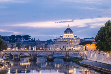 Evening view of St. Peter's Basilica and illuminated bridge over the Tiber River in Rome