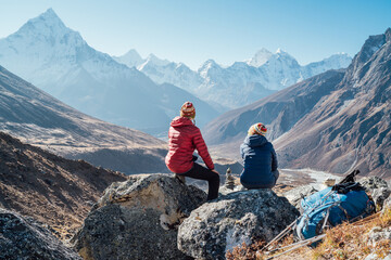 Couple resting on the Everest Base Camp trekking route near Dughla 4620m. Backpackers left...