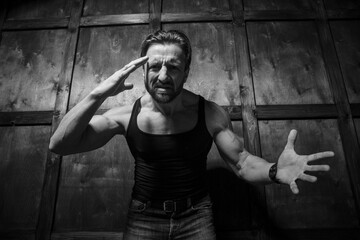 Under a dim light, a muscular man showcases his raw emotions, combining strength with tenderness as he passionately conveys his feelings in a rustic setting, highlighting an unexpected romance.