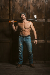 In a rustic setting, a muscular man stands confidently against a weathered wooden wall, holding an ax.
