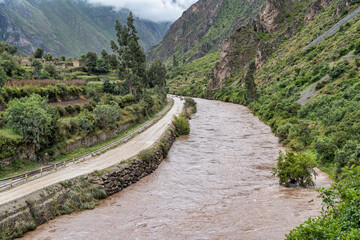 Scenic view of the Urubamba River flowing through the Sacred Valley alongside the Ollantaytambo town, Peru.