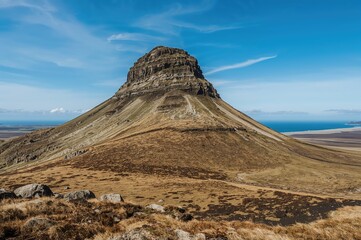 Lush moss and lichen cloak a rugged volcanic peak under a bright autumn sky.