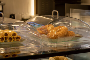 Fragment of glass showcase with sweets in coffee shop, close-up, selective focus.