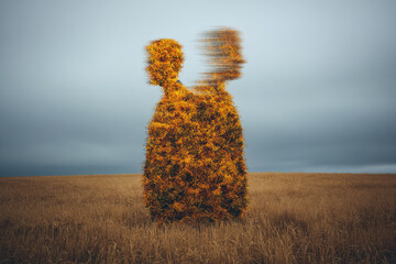 Surreal silhouette of two people merging, formed by vibrant yellow flowers, standing in golden field under cloudy sky, evoking sense of unity and transformation