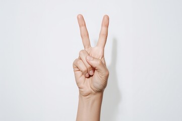 Hand showing a peace gesture on a plain white background