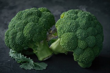Two fresh green broccoli crowns resting on a dark background, symbolizing nutrition and well-being.