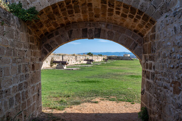 Looking through an arched walkway at Napolean's cannons on the Eastern Wall Promenade in Acre, Akko in Israel. 
