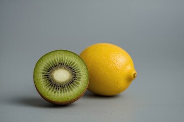 Yellow lemon and green kiwi on a neutral grey surface, representing nature and health, fruit, tropical, and diet