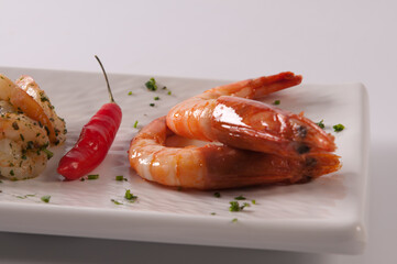 Chef de cozinha preparando um prato da culinaria mediterranea, com camaroes fritos no azeite, vinho branco e temperos
