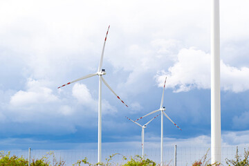 Wind turbines standing tall against a dramatic sky, showcasing renewable energy technology and sustainable practices in a natural landscape with lush greenery and vibrant clouds