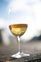 
Glass of red wine Cabernet Sauvignon from Chile supported on a bottle on the black wooden table with corkscrew beside it and with wine spilled on the wood.