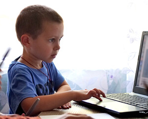 Child using a laptop computer - A Young Boy Sitting at a Desk and Using a Laptop Computer