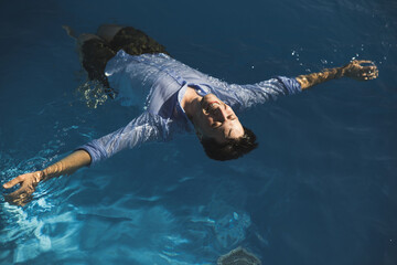 A Man Floating Relaxedly in a Pool Underwater, Enjoying the Peaceful Water Leisure Activity