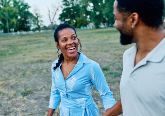 Obraz premium Happy active young black couple having fun walking running holding hands and bonding in park or nature outdoors
