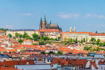 Obraz premium An aerial view across the rooftops towards the castle complex from the City Hall tower in the old town square in central Prague in springtime