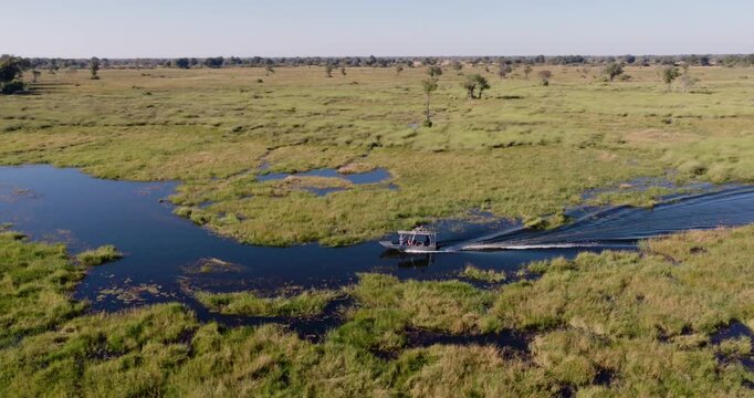 High aerial panning. Tourists on a sightseeing boat on a river in the Okavango Delta 