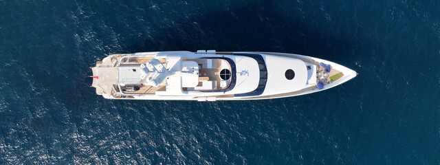 Aerial drone ultra wide top down photo of luxury yacht with wooden deck anchored in deep blue sea...