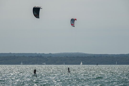 Hill Head England - September 6 2025: kite surfers in the Solent with yachts and The Isle of Wight in the background