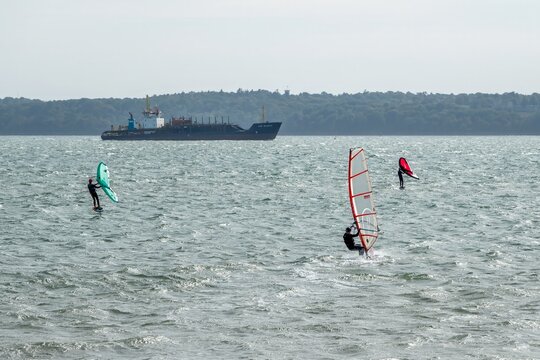 Hill Head England - September 6 2025: kite surfers in The Solent with UKD Bluefin dredger and The Isle of Wight in the background