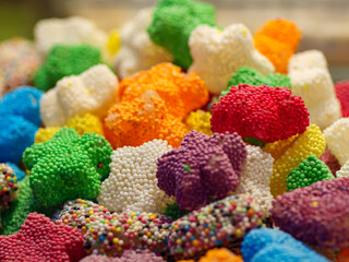 A vibrant assortment of multi colored gummy candies with a textured sugar coating is seen in a detailed close up a playful and delicious confectionery background