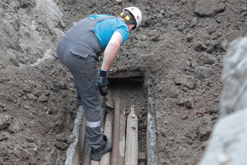 Male worker inspecting underground pipe system at construction site.