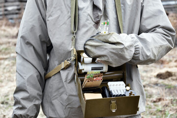 Protective gear with open metal case holding various tools in an outdoor setting.