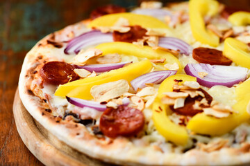 Pizza with chorizo ​​sausage, mozzarella cheese and yellow pepper. Rustic wooden background. Soft focus.	