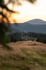 Sunset over a serene mountain village surrounded by dense forests and rolling hills. Hiking in Carpathian Mountains, Ukraine