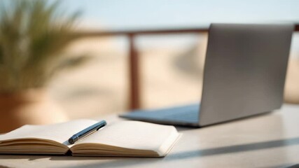 Open notebook with pen and laptop computer sit on a table on a sunny terrace overlooking a desert landscape. Ideal for digital nomads. Remote workers. Or families seeking a work and travel lifestyle - Powered by Adobe