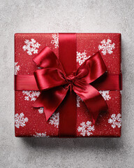A beautifully wrapped red gift box adorned with white snowflakes and a shiny ribbon, perfect for festive occasions.