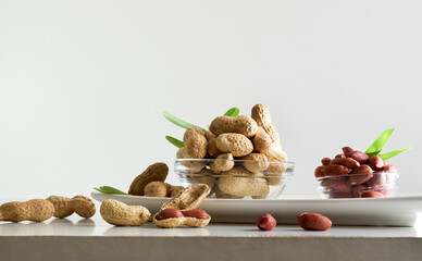 Peeled and unpeeled peanuts in glass bowls isolated on plate