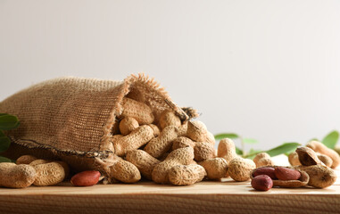 Cloth sack filled with peanuts scattered on table isolated background