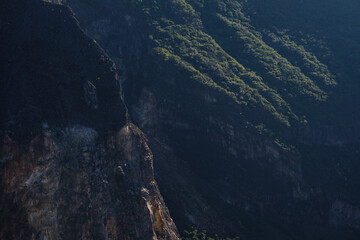 Steep Rocky Cliffs with Lush Green Vegetation in Daylight