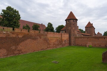 Historic brick castle with towers and green lawn in a cloudy sky setting