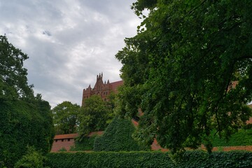 Historic castle towering above lush greenery under a cloudy sky in a serene landscape setting