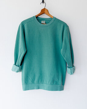 Cozy vintage-style kelly irish green crewneck sweatshirt on wooden hanger, back view, minimalist fashion apparel mockup for branding, clothing design, boutique, or online shop display