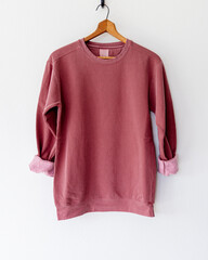 Cozy vintage-style maroon crimson red crewneck sweatshirt on wooden hanger, back view, minimalist...