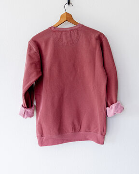 Cozy vintage-style maroon crimson red crewneck sweatshirt on wooden hanger, back view, minimalist fashion apparel mockup for branding, clothing design, boutique, or online shop display