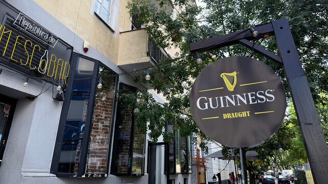 Warsaw, Poland - September 09, 2025: Guinness Draught sign outside a bar with greenery and urban setting
