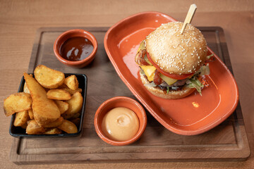 Gourmet burger with crispy wedges and warm dipping sauces
