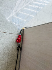 A vibrant red and black cord is securely attached to a sturdy wooden surface, ensuring reliable...