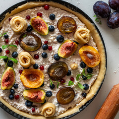 Raw tart or open summer pie with figs, prunes, apricots and blueberries is ready to bake in a round mold. Close-up. View from above. High quality photo