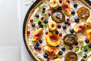 Raw tart or open summer pie with figs, prunes, apricots and blueberries is ready to bake in a round mold. Close-up. View from above. High quality photo