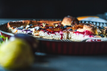 A delicious berry dessert, a piece of tart or an open sweet pie with figs, blueberries and apricots on a black plate. High quality photo
