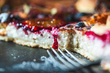 A delicious berry dessert, a piece of tart or an open sweet pie with figs, blueberries and apricots on a black plate. High quality photo